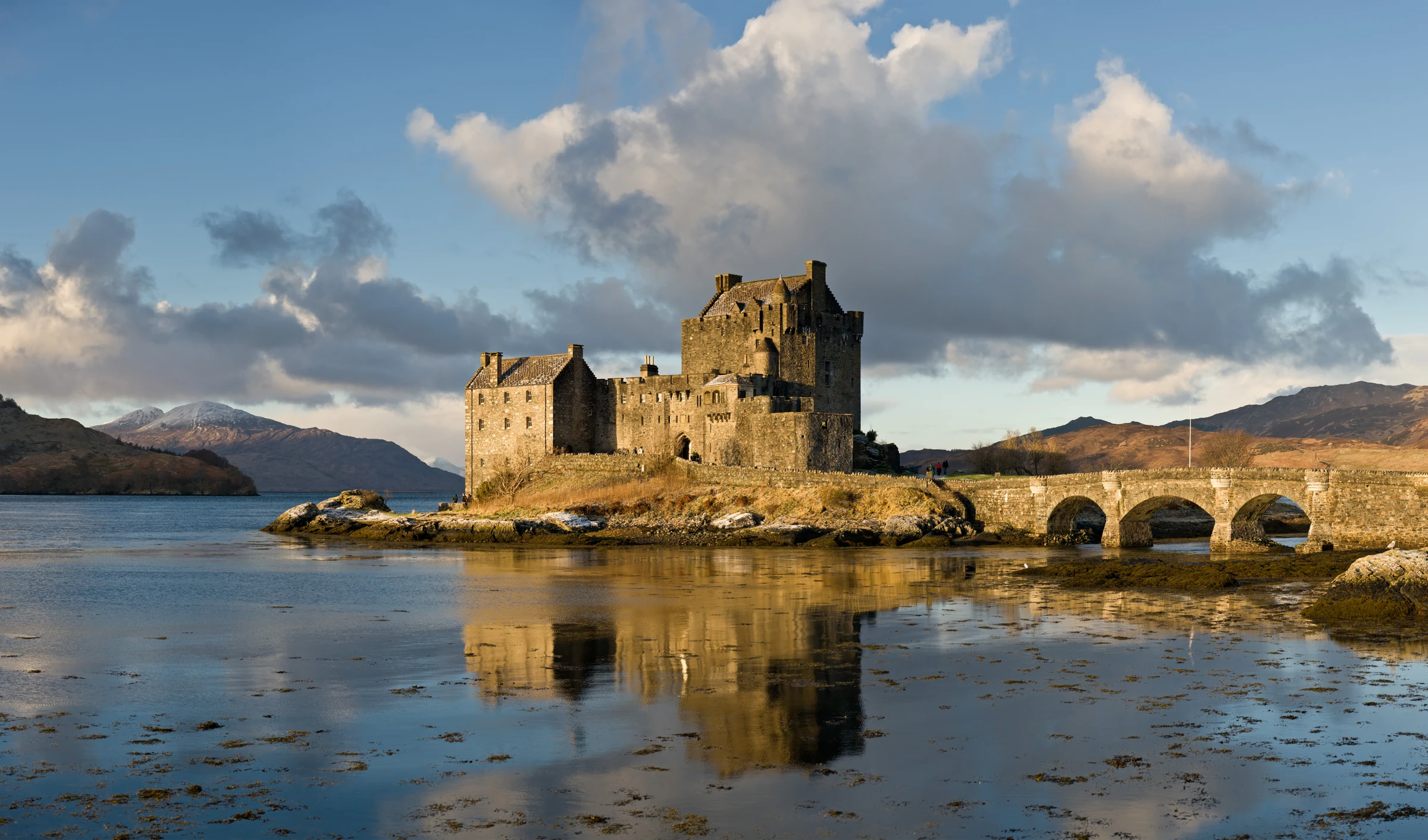 Castelo Eilean Donan e sua ponte refletidos no loch, fotografados por David Iliff ao amanhecer em janeiro de 2011