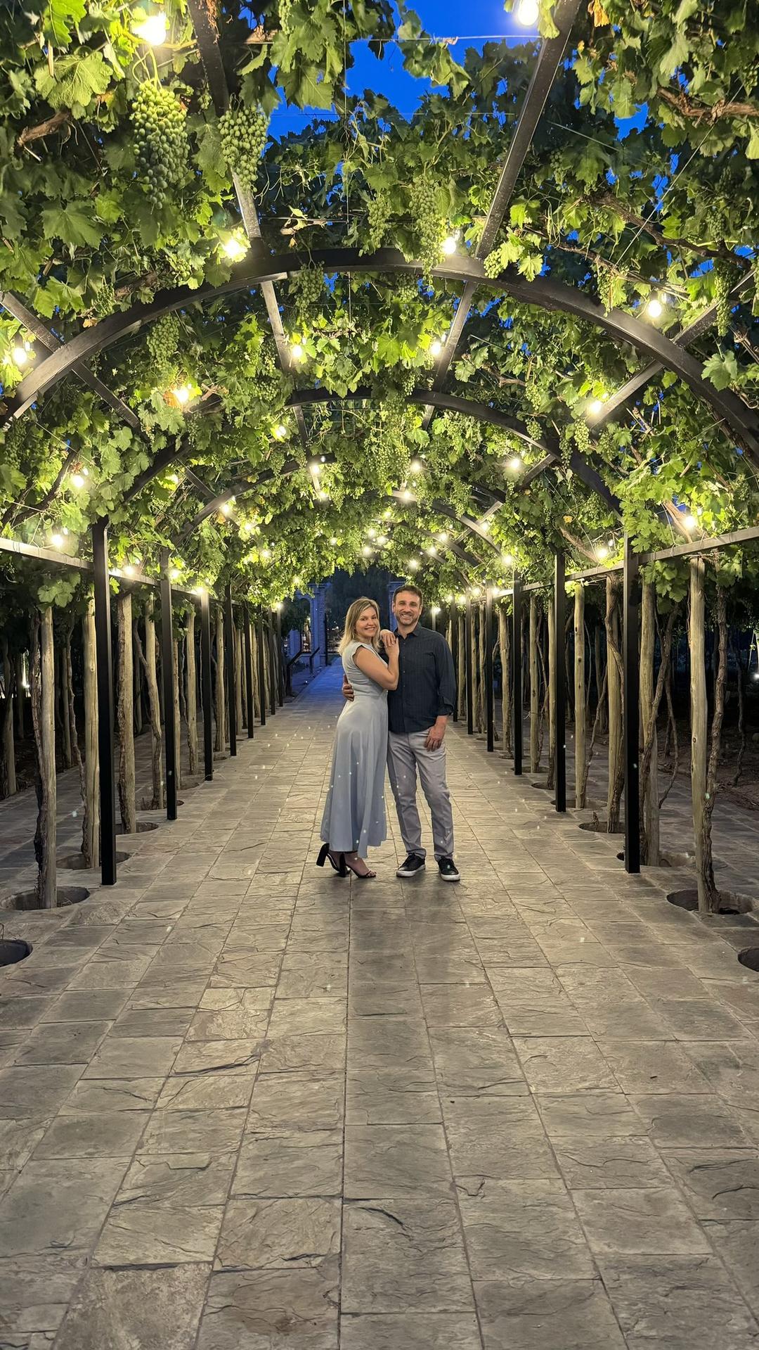 Casal em tunel de parreiras iluminado a noite em Mendoza